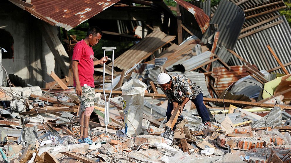 Personer som letar i förstörda husrester.