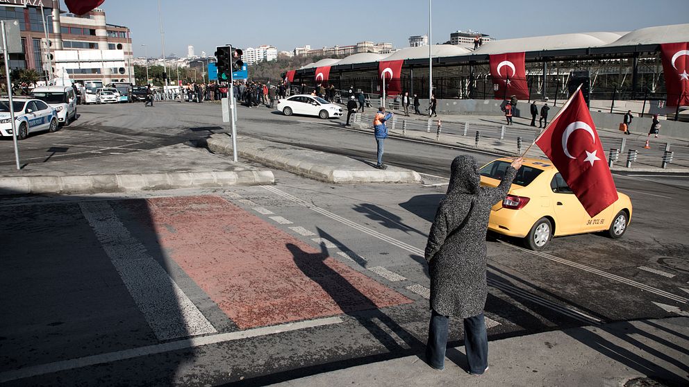 En person med en Turkisk flagga utanför stadion.