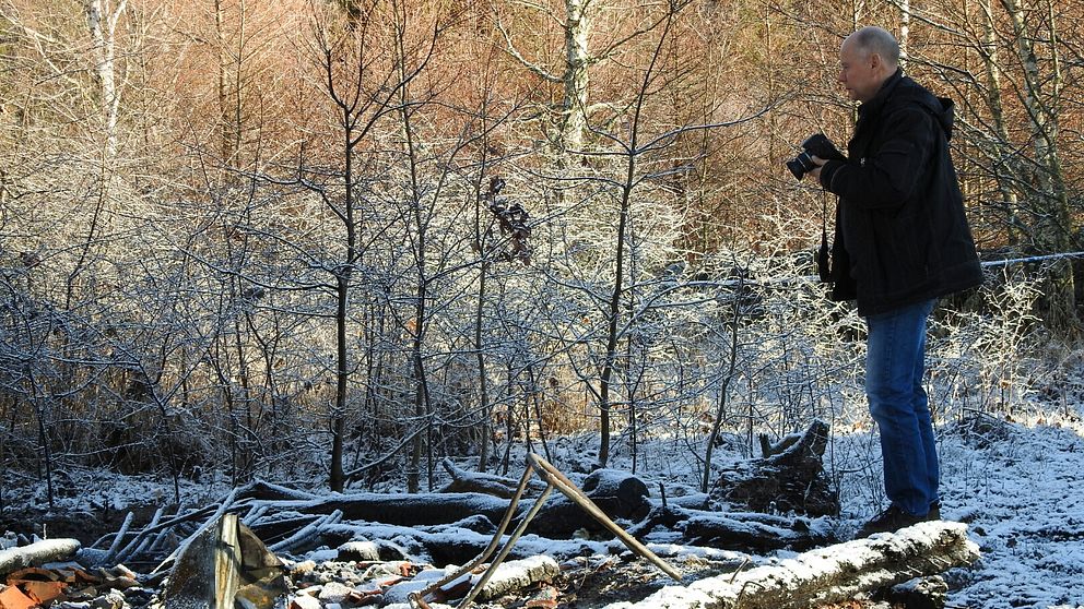 Man med kamera vid snöig brandplats