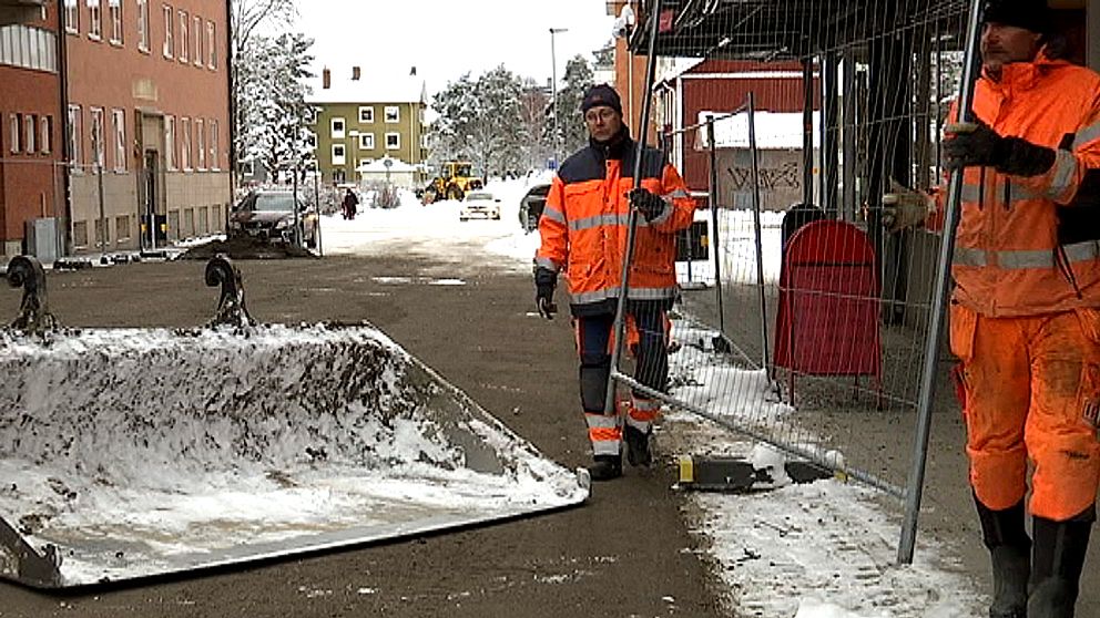 Två arbetare i varselkläder plockar bort staket.