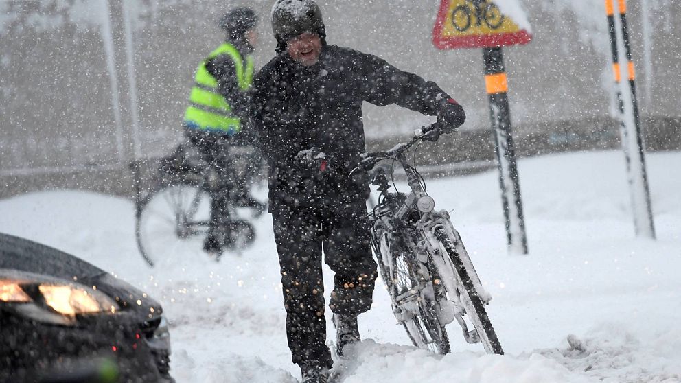 Cyklist leder cykel i snöoväder