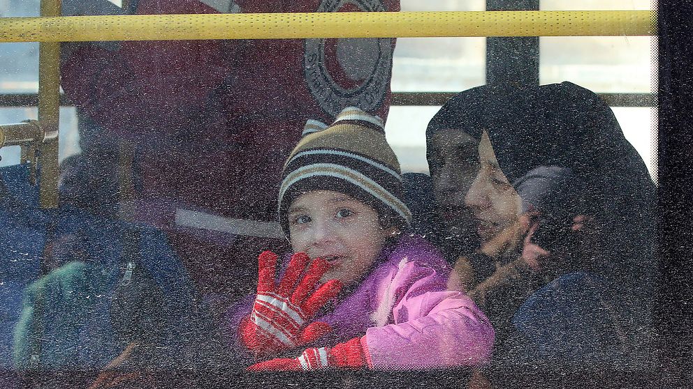 Ett barn vinkar inifrån en av bussarna som evakuerar människor från östra Aleppo.