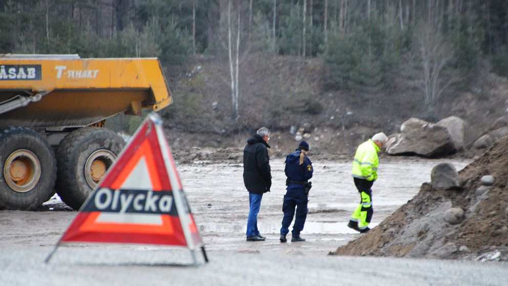 Olyckstriangel och fordon med personer i bakgrunden