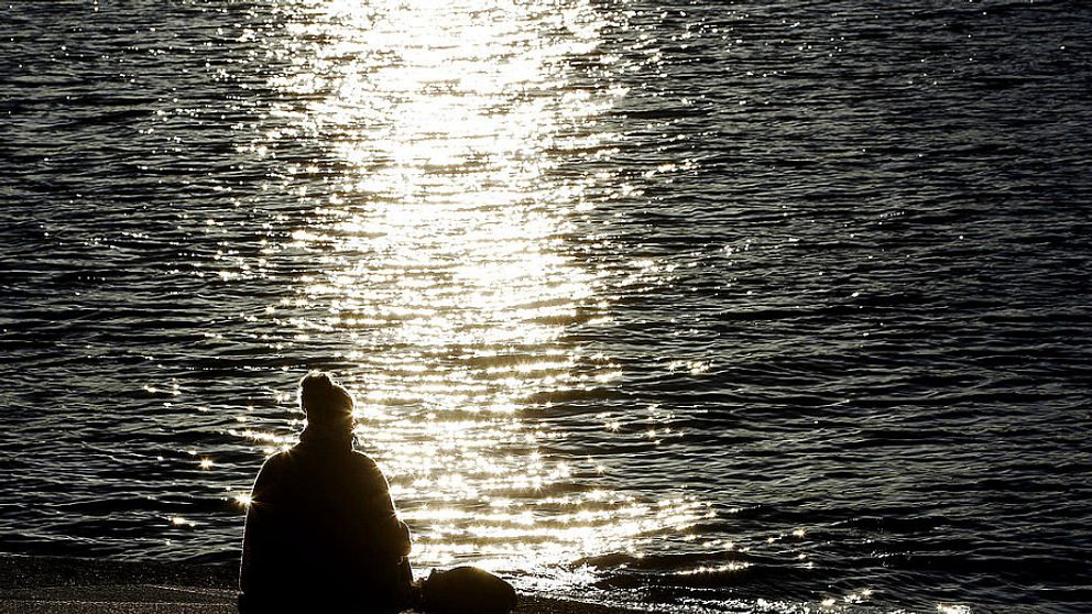 Kvinna sitter vid vatten