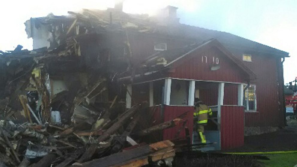 En  brandman är på väg in i annexet, som är till hälften rivet