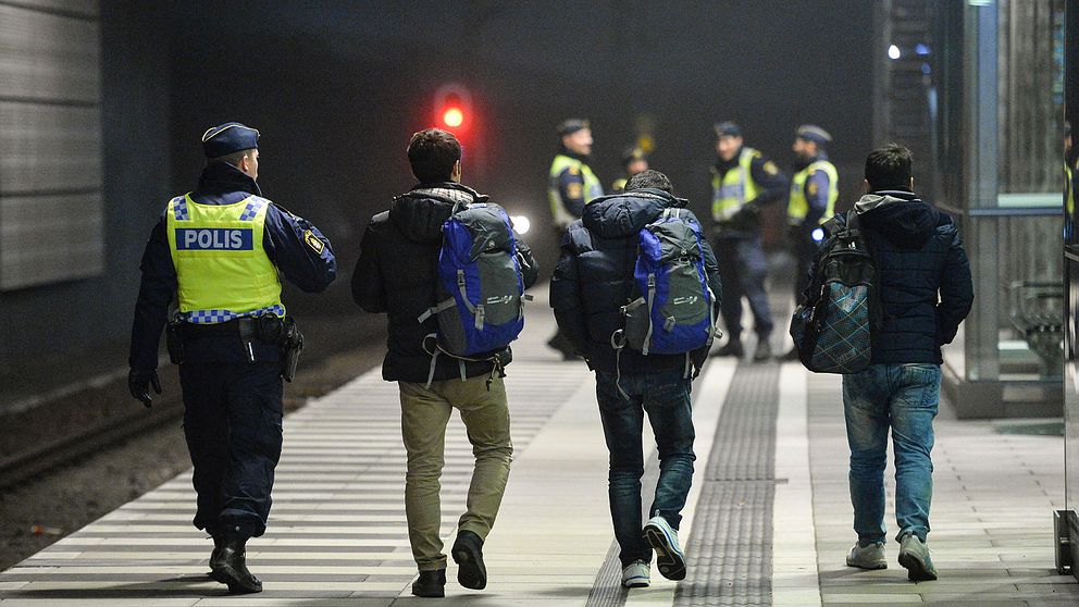 Polis eskorterar asylsökande efter genomförd gränskontroll.