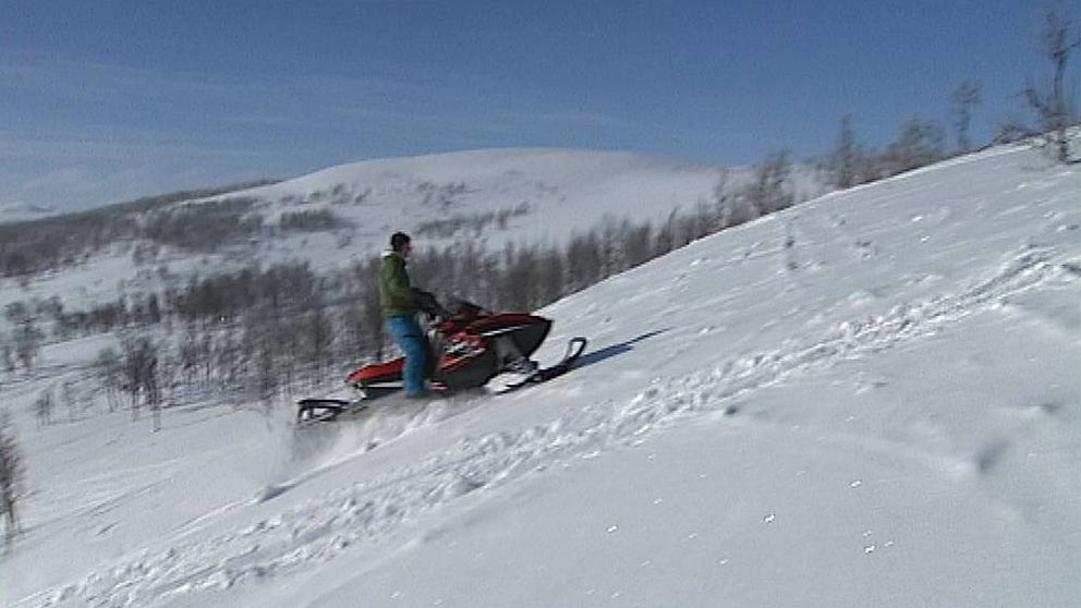 bild på skoteråkare som kör uppför ett fjäll