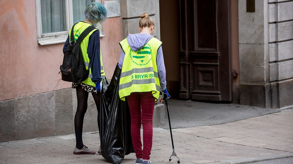 Ungdomar plockar skräp på gatan.