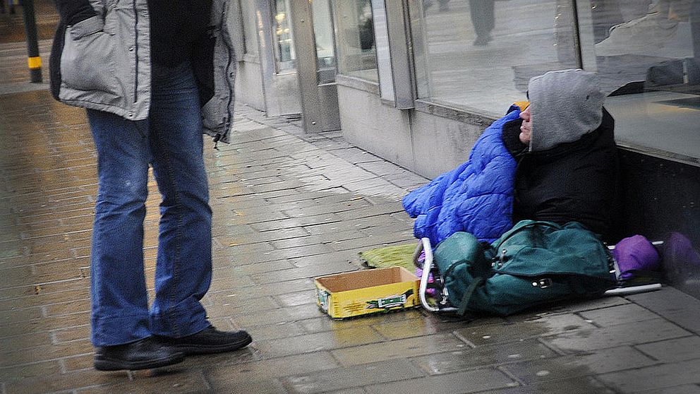 En hemlös person som ligger på en gata.