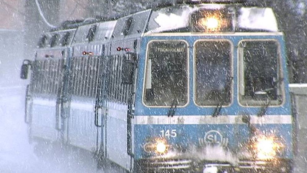 Roslagsbanan. Arkivbild på ett litet blått tåg som kör genom ett kraftigt snöfall.