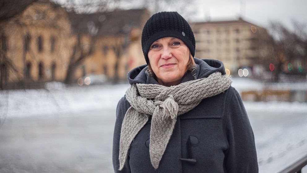 Ett porträtt på Kristin Spolander, chef ABF Uppsala län. Hon står utomhus vid svandammen i Uppsala. Svart mössa och grå halsduk. Hon har en grå kappa på sig.