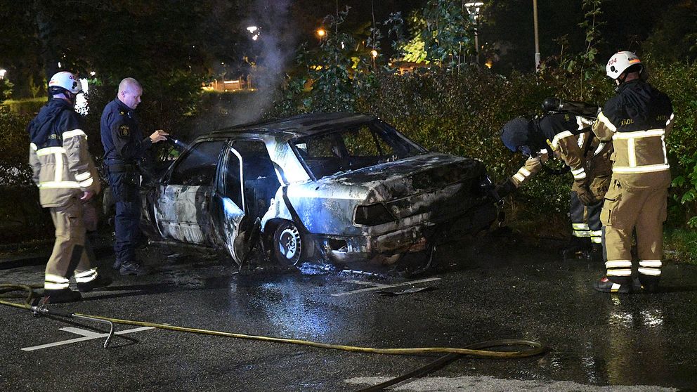 Räddningstjänst och polis kontrollerar en utbränd bil på Kärleksvägen i Burlöv.