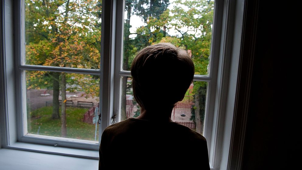 Ensam pojke vid ett fönster.