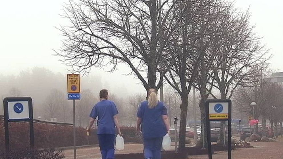 Två sjuksköterskor går med vattendunkar