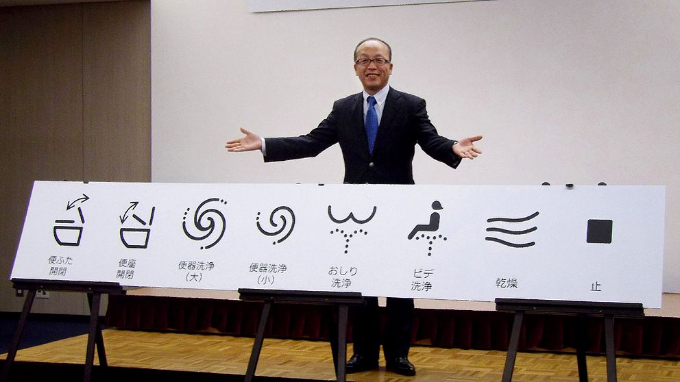 Madoka Kitamura, ordföranden på Branschorganisationen för japansk sanitetsutrustnings-industri, visar upp de nya symbolerna.