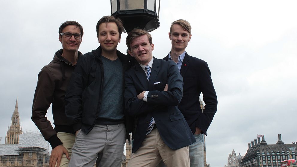 fyra unga män poserar vid lyktstolpe i London.