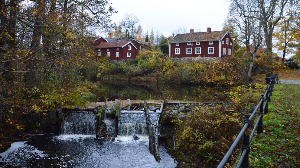 Vatten som rinner vid dammen i Järle kvarn. Bebyggelse i bakgrunden.