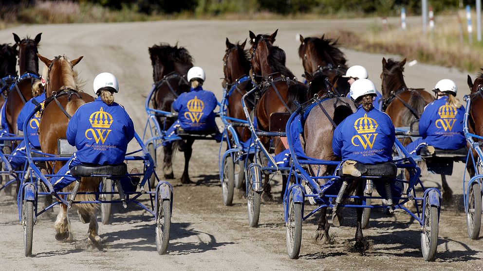 flera travekipage på bana sedda bakifrån, likadana jackor med emblem