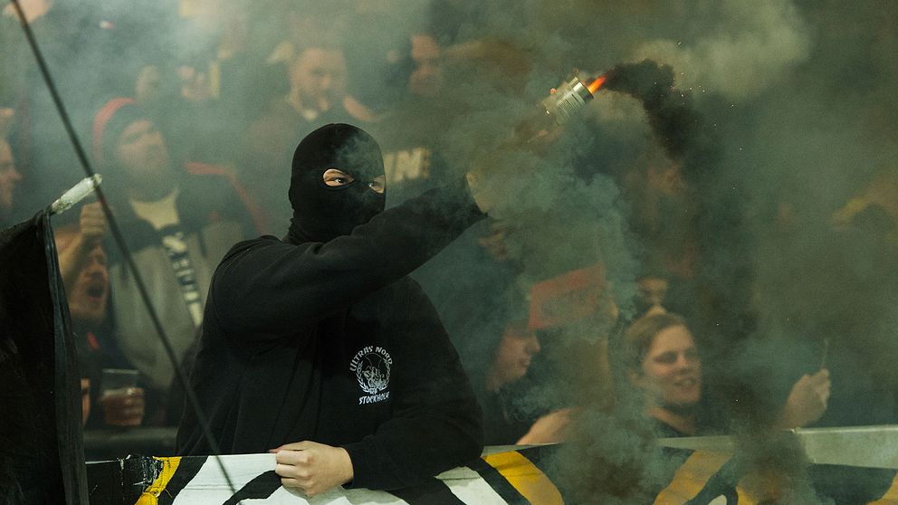 Maskerad supporter tänder pyroteknik under en AIK-match i fotbollsallsvenskan.