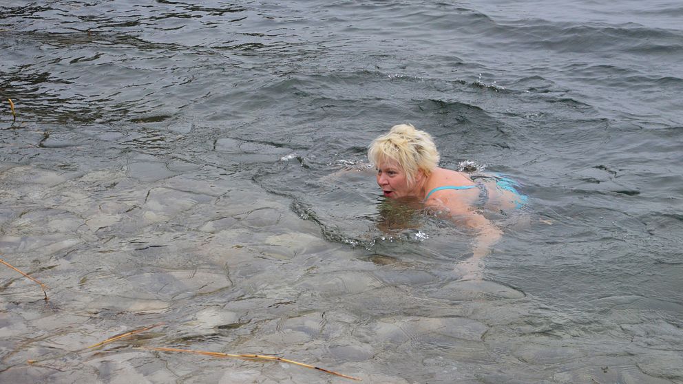 Carina Fransson tar sig ett vinterbad i Vättern. Hon är ute på öppet vatten, men mindre isflak syns i nederkanten av bilden.