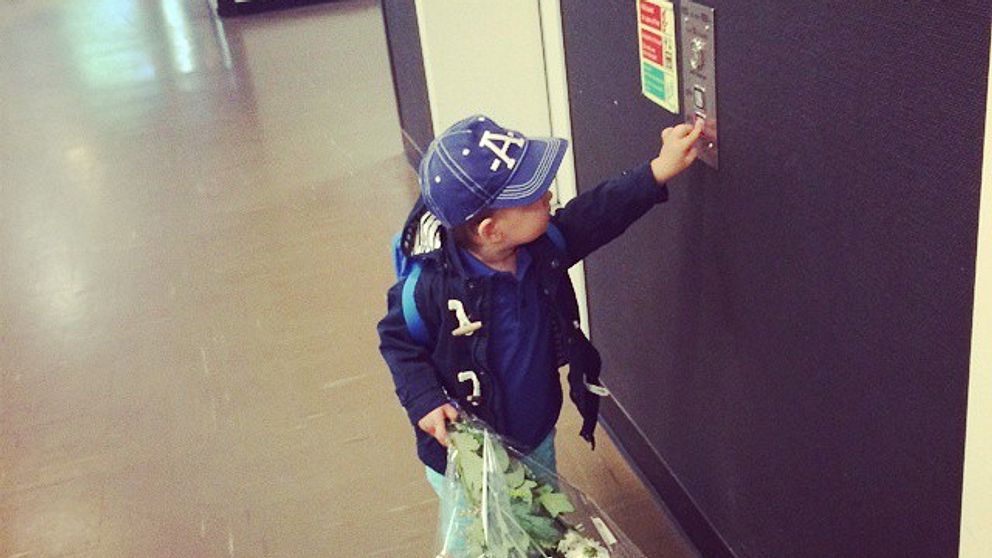 Pojke med blommor trycker på hissknappen