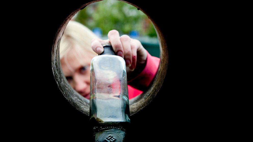 En kvinna lägger i en glasflaska i en glasigloo.