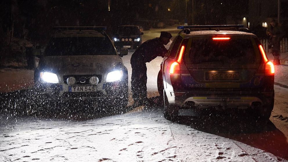 Två polisbilar och en polisman som böjer sig fram mot en bildörr