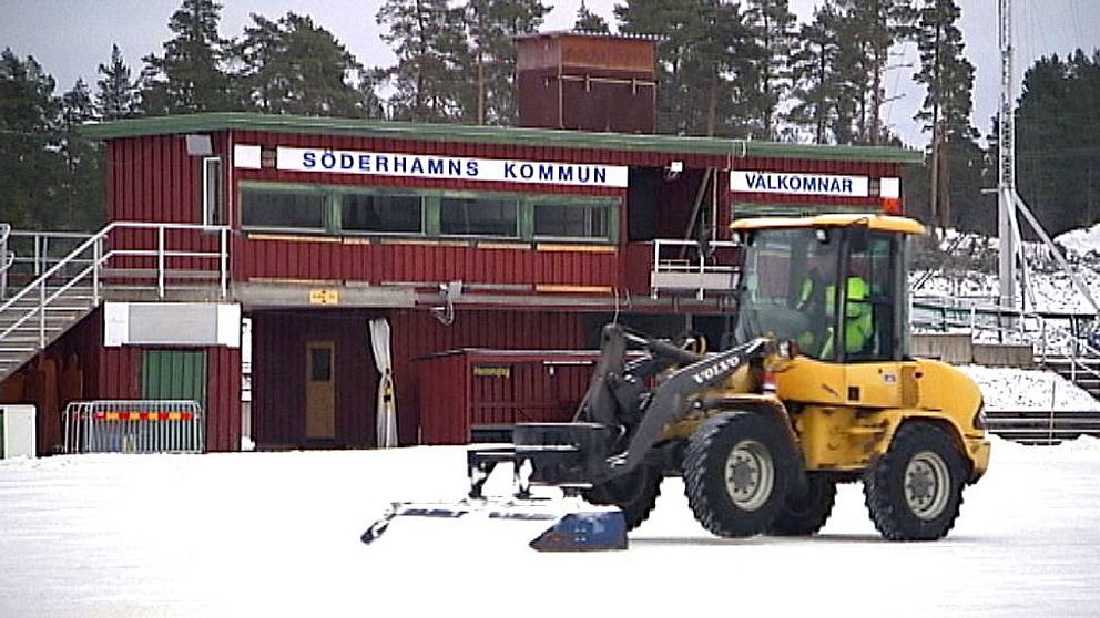 En traktor skottar bort snö från en is.