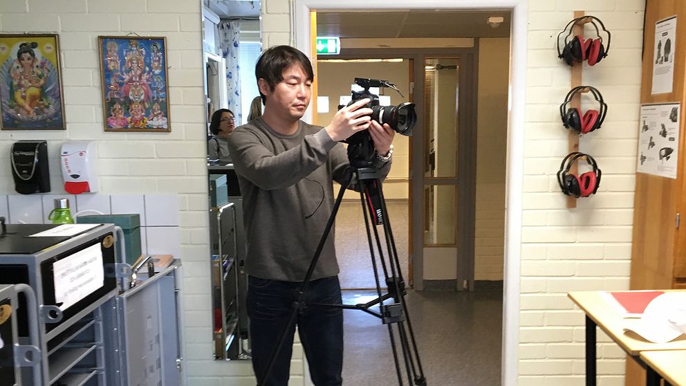 Producent Jeong Won Seok filmar klassrummet med en kamera som står på ett stativ.