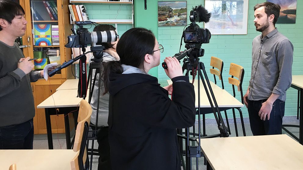 Flera personer står och filmar och intervjuar en reporter från SVT i ett klassrum.