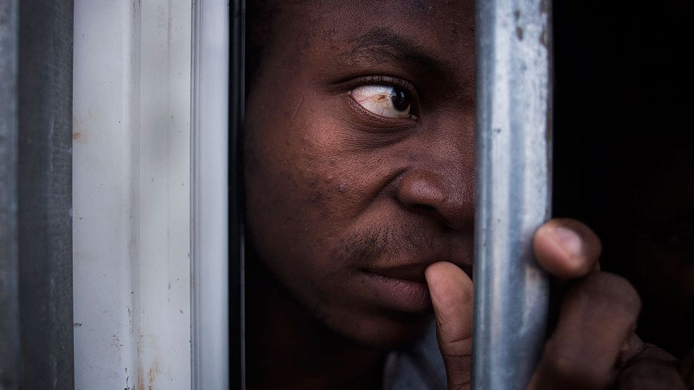 En okänd migrant hålls fången i en bur i interneringslägret i Gharyan