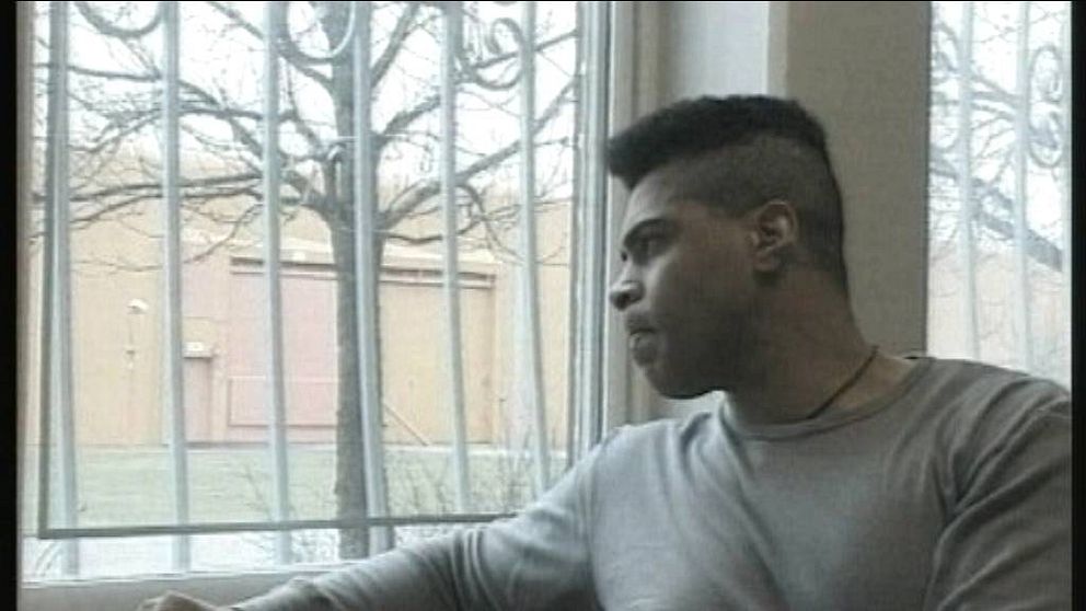 en man tittar ut genom fönster med galler
