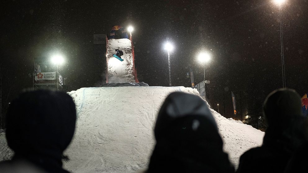 snowboardåkare som hoppar från ramp, åskådare i förgrund