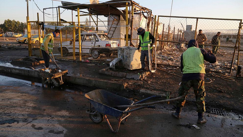 Kommunalarbetare städar upp efter bombdådet i Bagdad i dag.