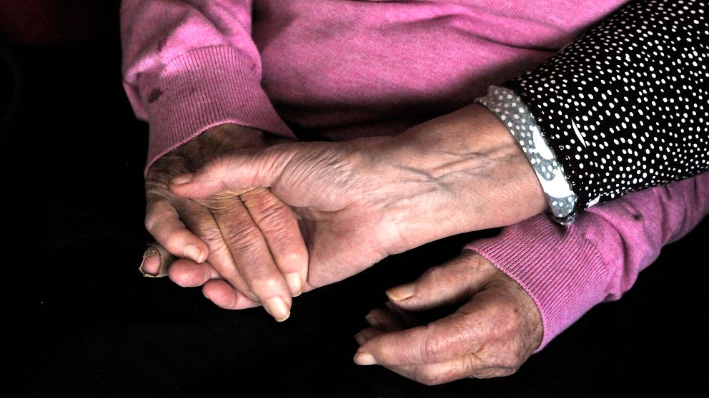Yngre kvinna håller äldre kvinna i handen
