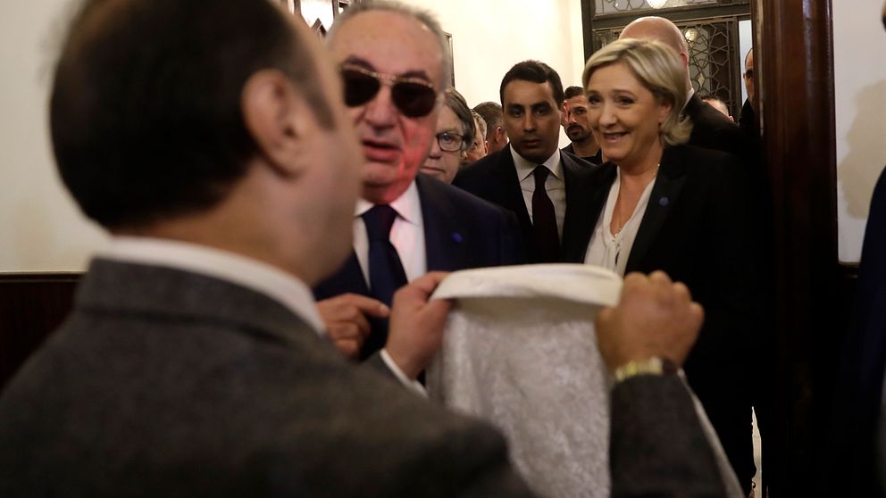 En man håller upp en slöja mot det franska partiet Nationella frontens partiledare Marine Le Pen