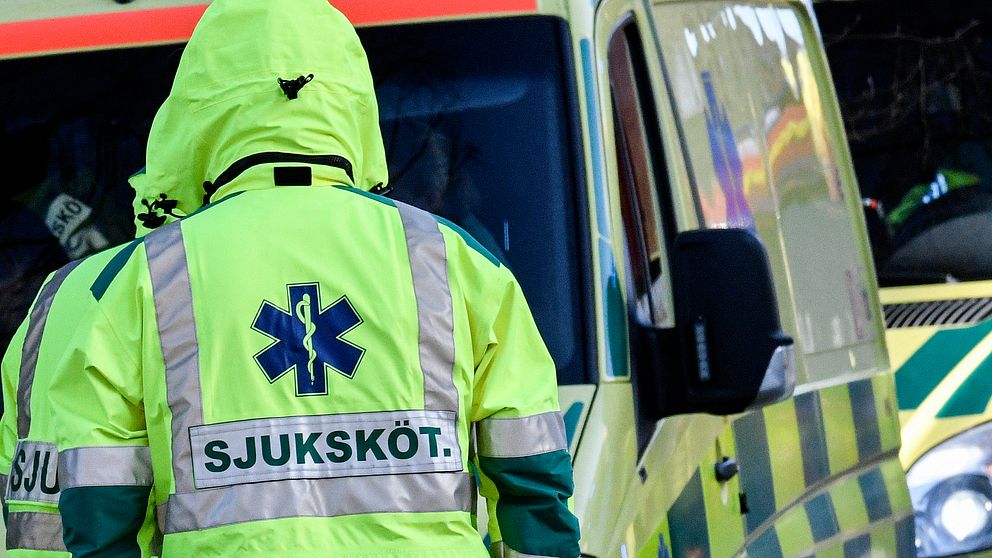 En ambulanspersonal som står med ryggen mot kameran. Arkivbild