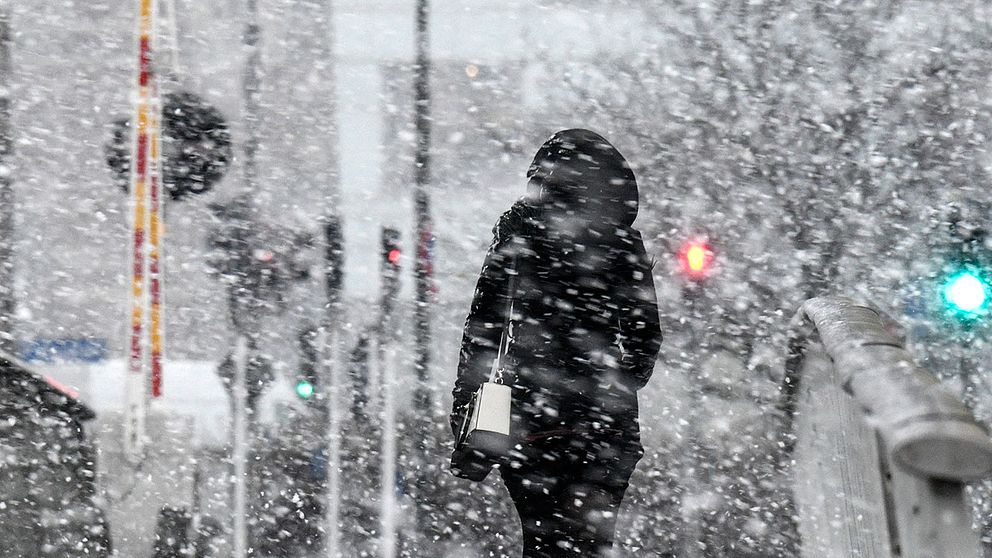 Person promenerar genom snöoväder.