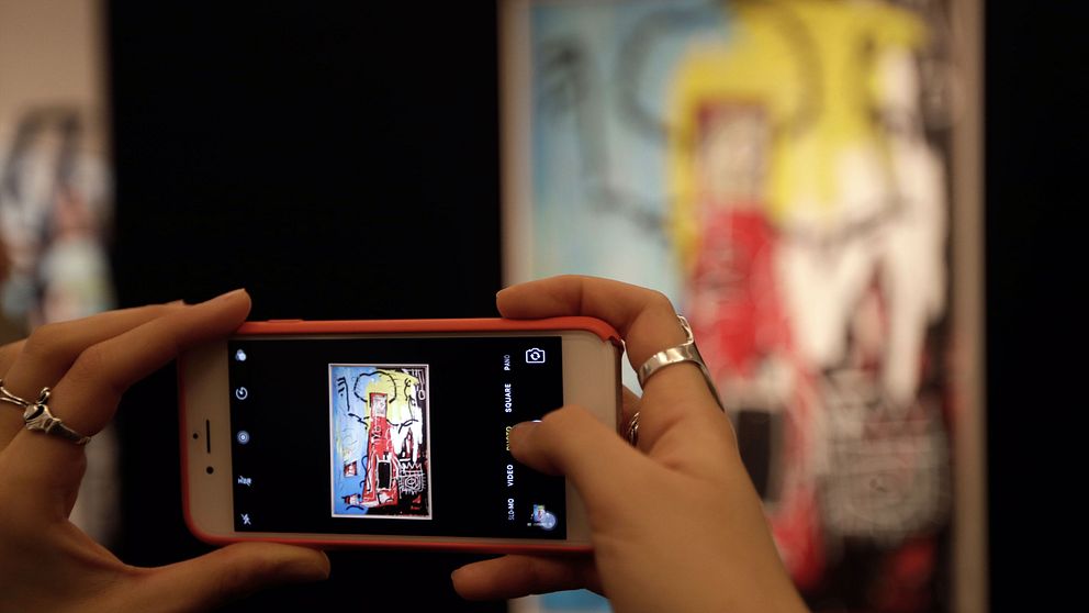 Person som fotograferar Jean-Michel Basquiats verk ”Untitled (One Eyed Man or Xerox Face)” under konstauktion i London.