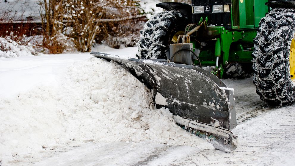 Traktor plogar upp snö.