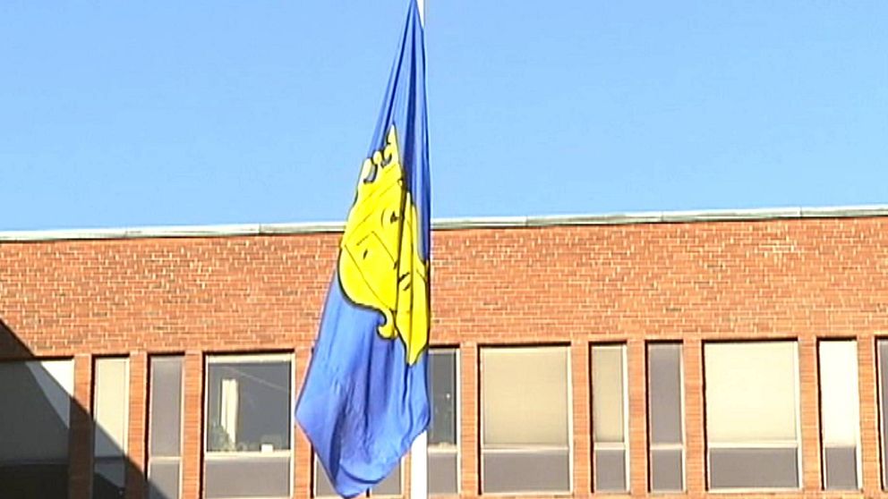 Stockholms stads flagga i förgrunden mot blå himmel, i bakgrunden tegelbyggnad som är Tekniska nämndhuset.