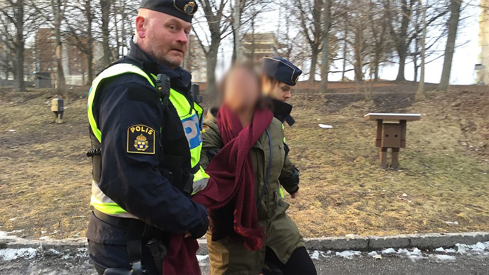 Polis eskorterar en demonstrant från AKP-mötet i Fittja.
