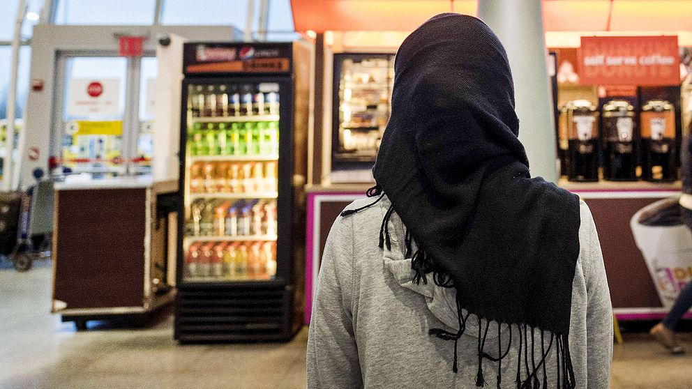 En kvinna med hijab framför ett kafé.