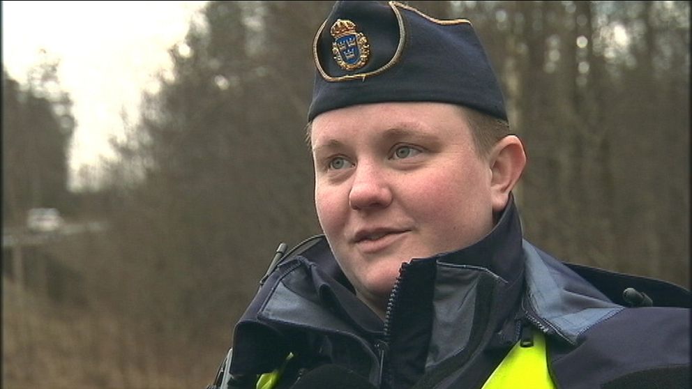 polisen Emma Englund står i sin uniform framför en skogsdunge.