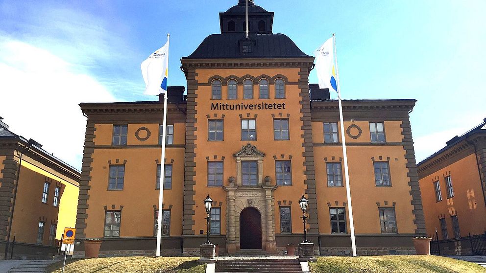 vy över universitetet – pampig äldre byggnad, flaggor framför