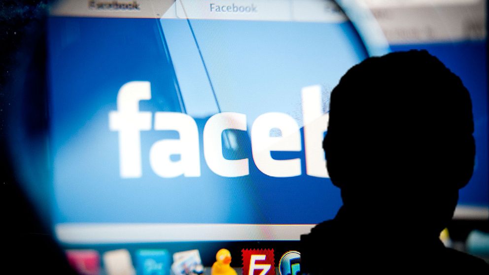 En silhouette framför Facebooks logotyp på en datorskärm.