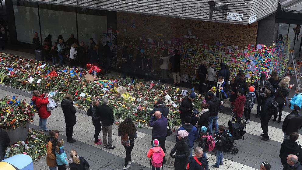 Människor och blommor vid hörnet utanför Åhléns på Drottninggatan.