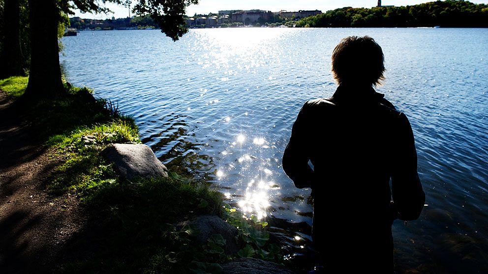 STOCKHOLM 20 100 922 : Silhuetten av en deprimerad kvinna som står vid ett träd och tittar ut över vattnet Foto: Jessica Gow / SCANPIX / Kod 10170