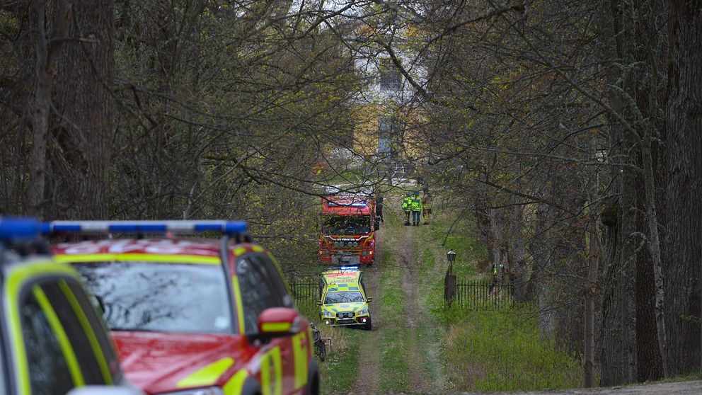 Räddningstjänstens bilar, polisbil och brandbil i allén mot Regnaholms slott