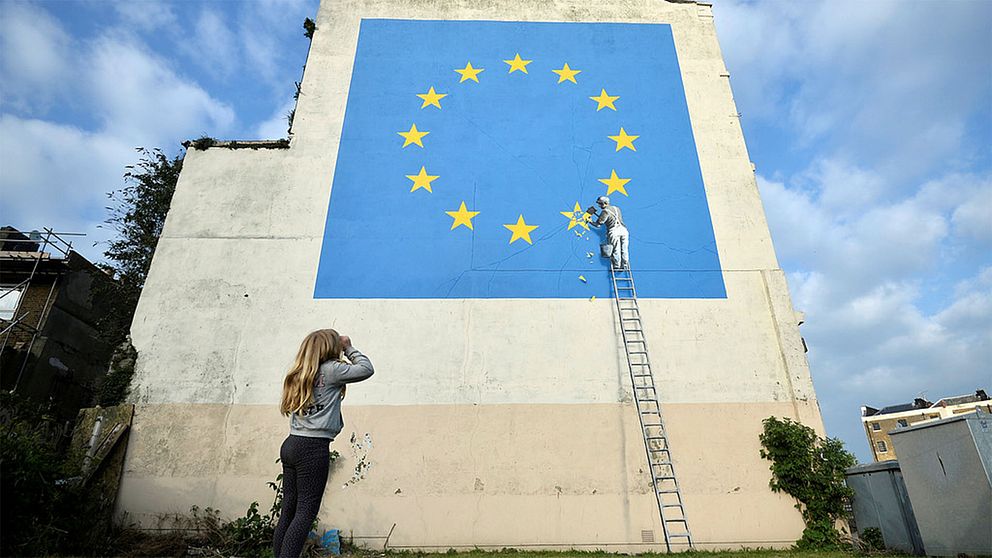 Den brittiske gatukonstnären Banksy gör ett inlägg i brexitdebatten på en husvägg i Dover.